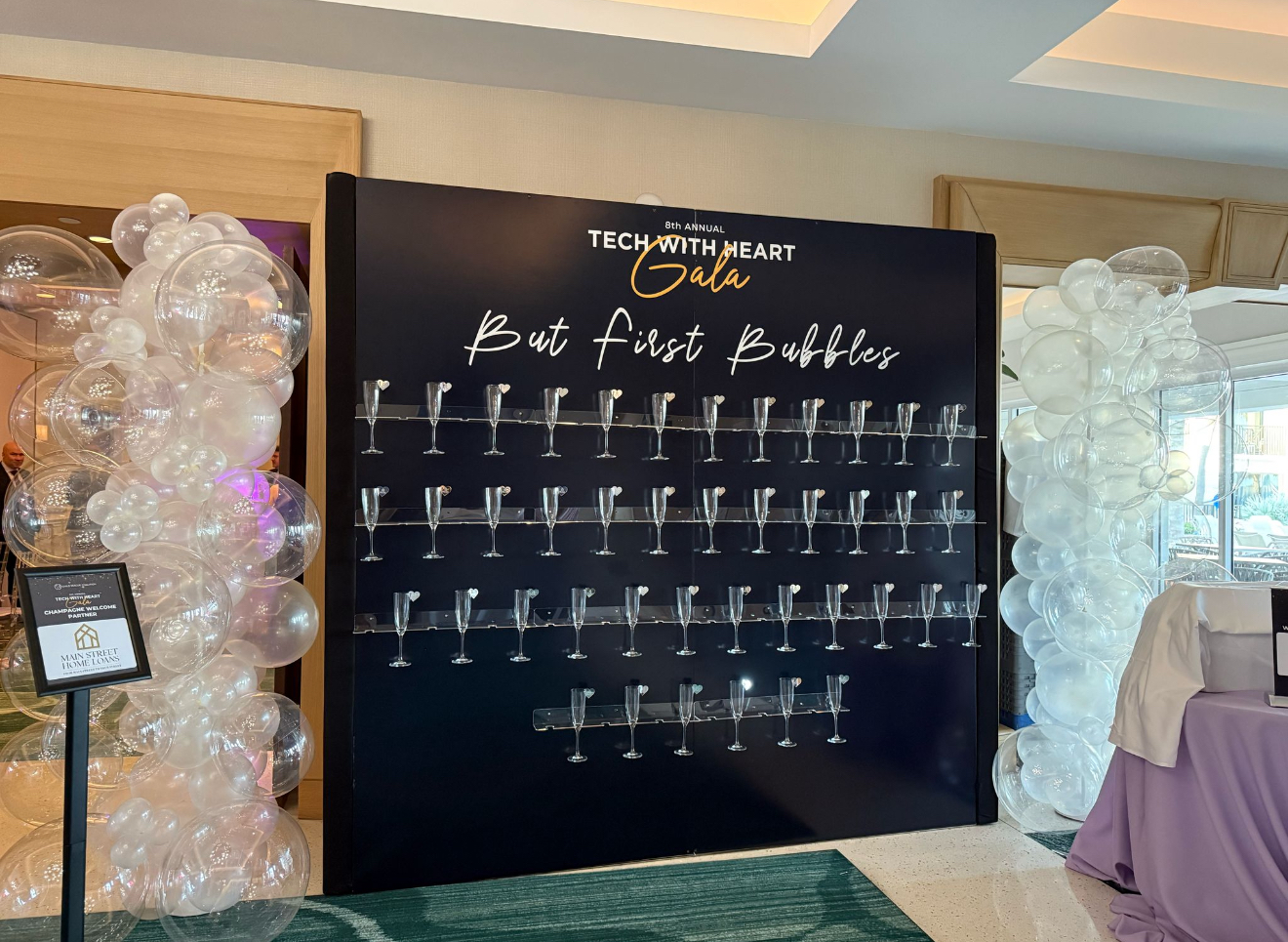 Custom champagne glass wall with printed gala graphics and balloon columns