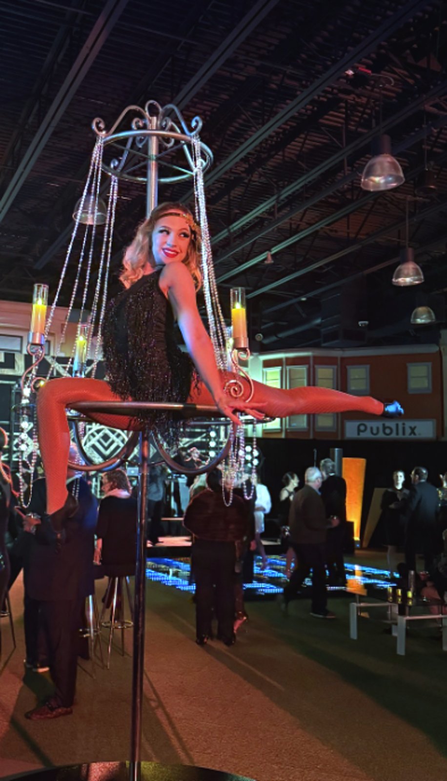Aerialist pouring champagne from a hanging chandelier lyra