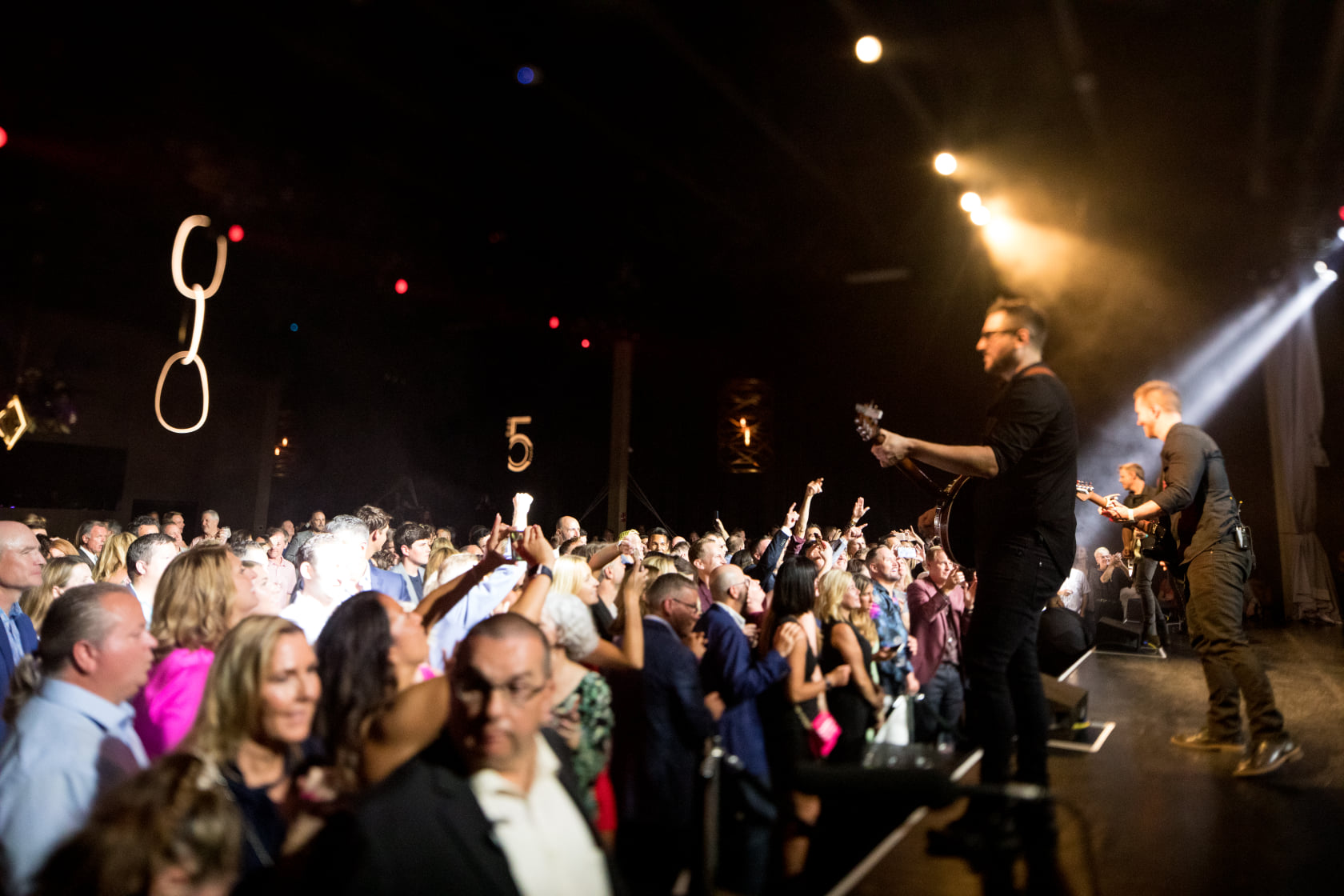 Band frontman performing at the edge of the stage with guests crowded in