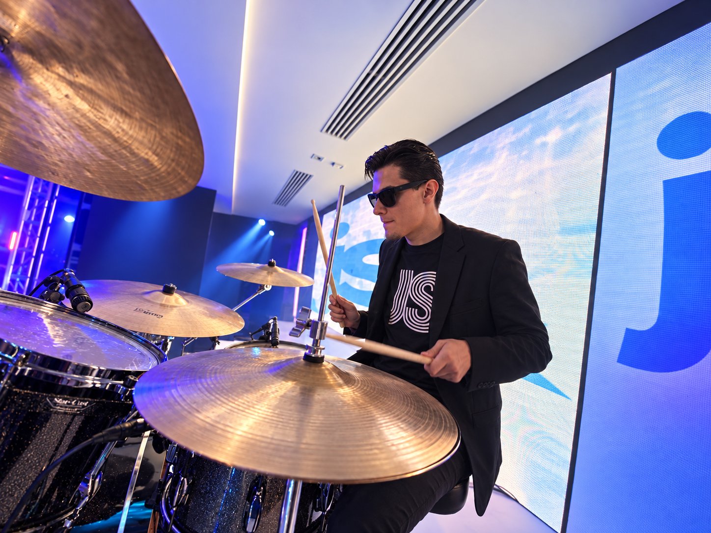 Drummer performing under blue-violet stage light