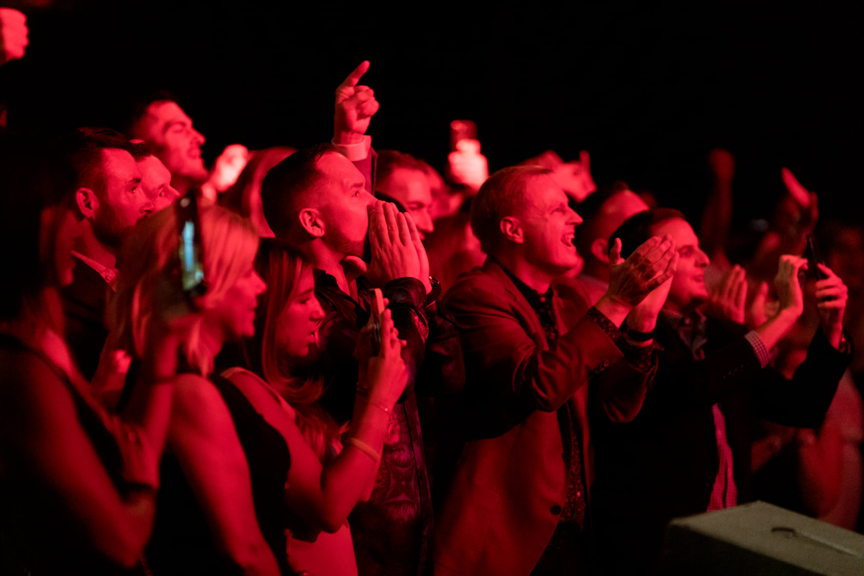 Guests dancing under deep red concert lighting during a private show