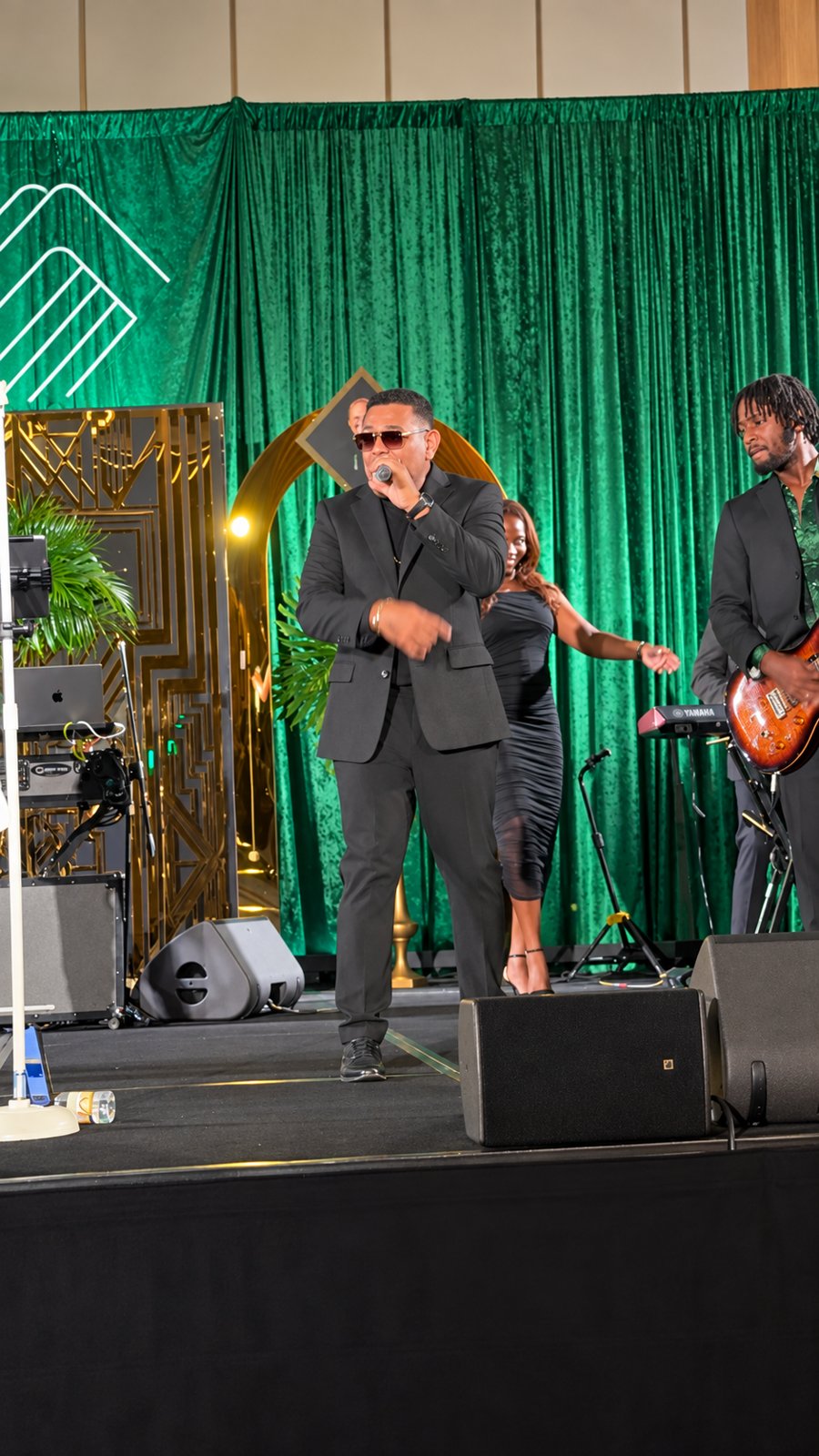 Live band performing on a stage with emerald drapery