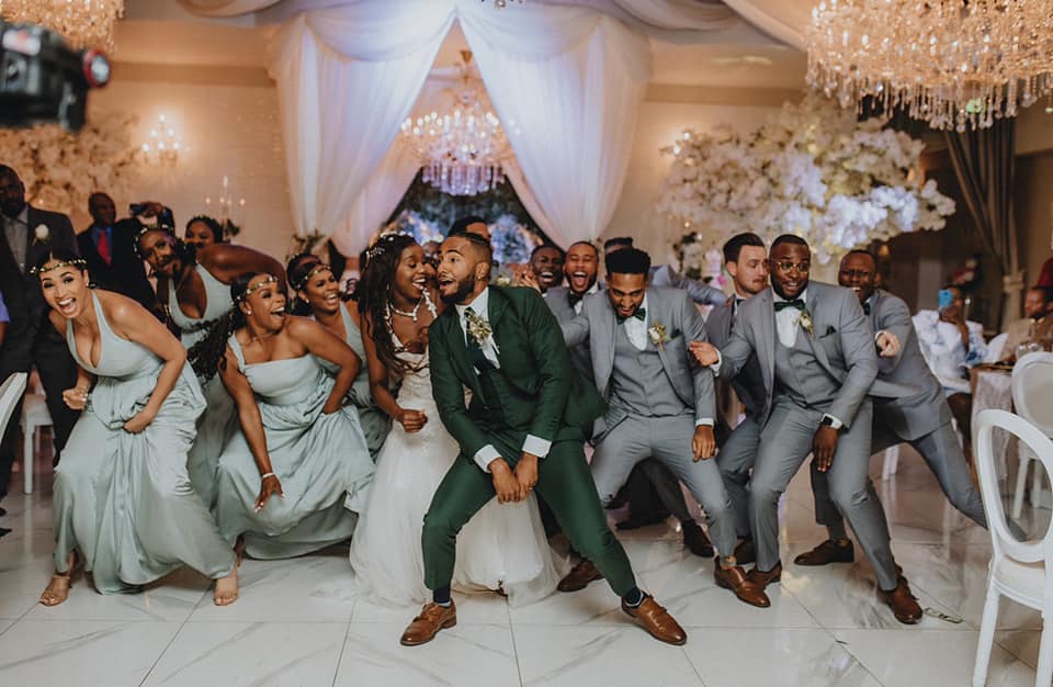 Wedding party celebrating on the dance floor under draping and chandeliers