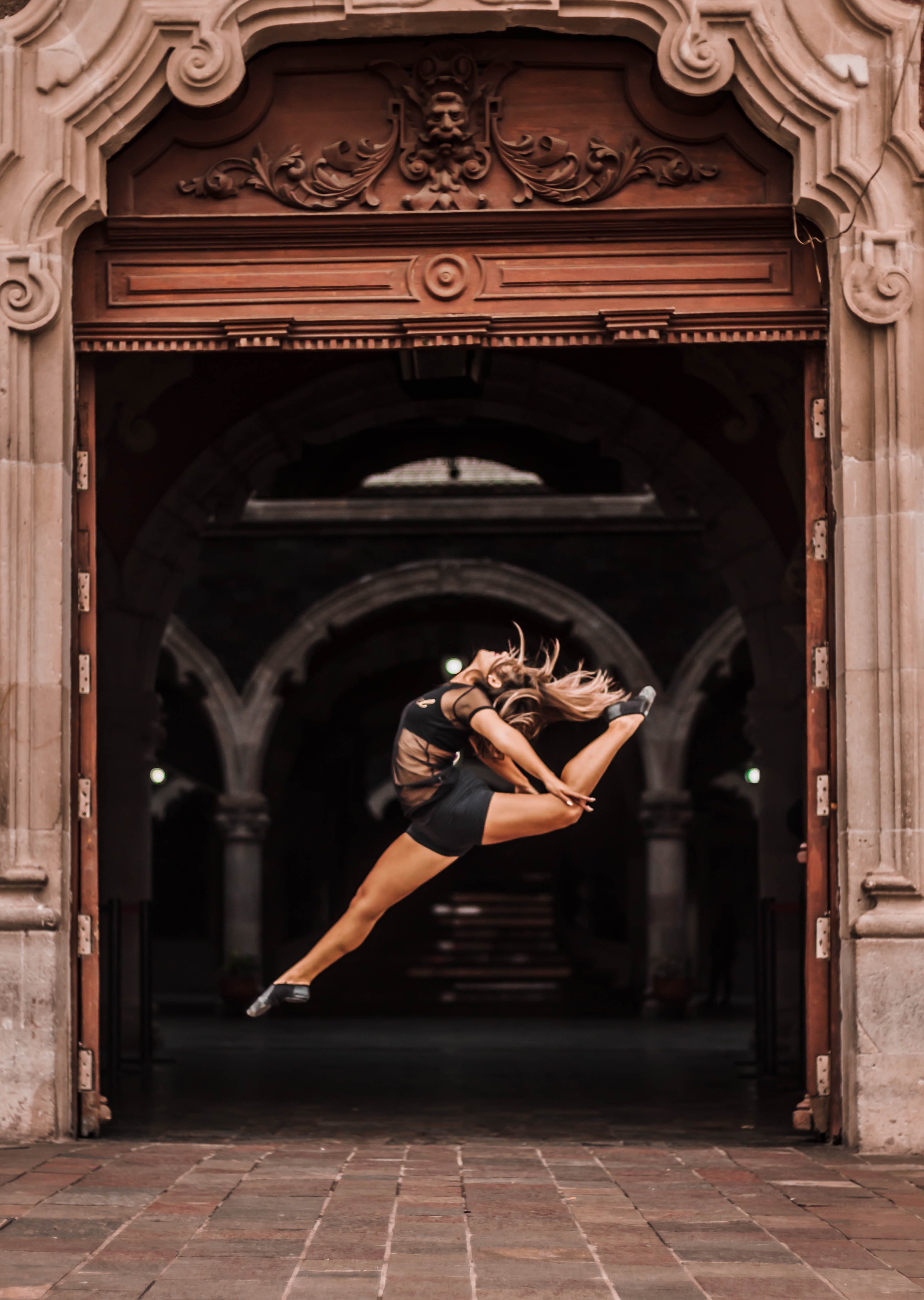 Contemporary dancer leaping mid-air inside a historic stone archway